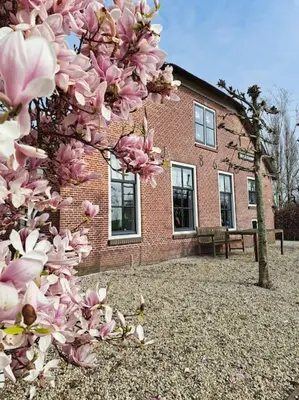 a tree with pink flowers in front of a brick building at Riante Boerderij in Het Groene Hart Regio Utrecht in Oudewater