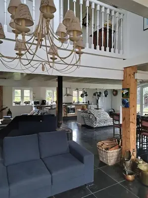 a living room with a blue couch and a chandelier at Riante Boerderij in Het Groene Hart Regio Utrecht in Oudewater