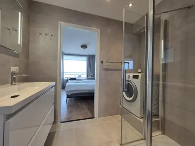 a bathroom with a sink and a washing machine at Sterflat aan Zee in Egmond aan Zee