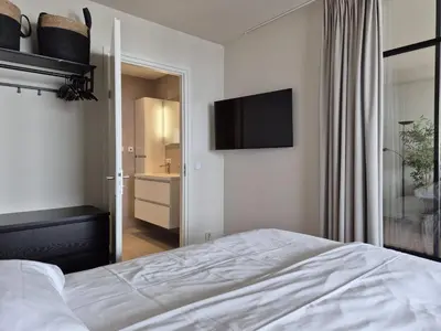 a bedroom with a bed and a television on the wall at Sterflat aan Zee in Egmond aan Zee