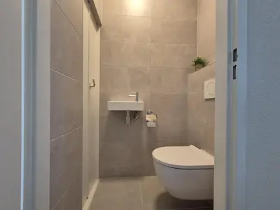 a small bathroom with a toilet and a sink at Sterflat aan Zee in Egmond aan Zee