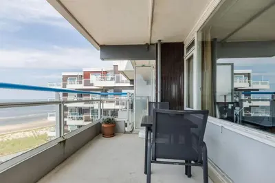 a black chair on a balcony with a view of the ocean at Sterflat aan Zee in Egmond aan Zee