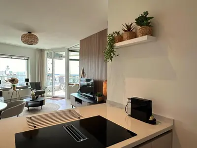 a living room with a kitchen and a living room with a tv at Sterflat aan Zee in Egmond aan Zee