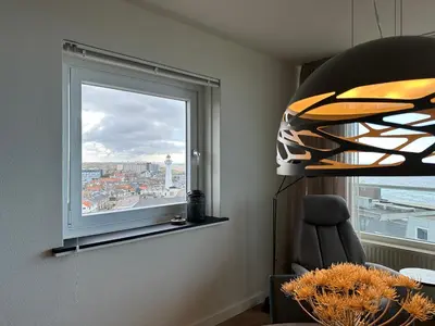 a room with a window and a chair with a view at Sterflat aan Zee in Egmond aan Zee