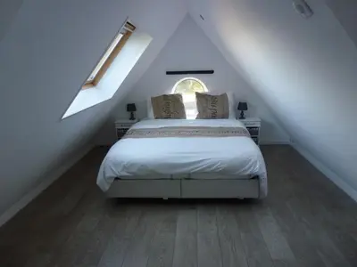 a bedroom with a bed in a attic with a window at Schiphol Apartments in Aalsmeer