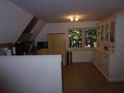a kitchen with white walls and wooden floors and windows at Schiphol Apartments in Aalsmeer