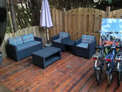 a deck with three chairs and an umbrella and bikes at Schiphol Apartments in Aalsmeer