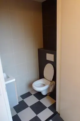 a bathroom with a toilet with a black and white floor at Schiphol Apartments in Aalsmeer