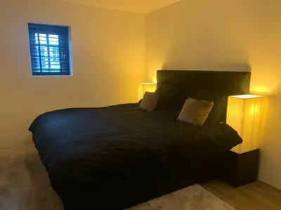 a bedroom with a large black bed with two lamps at tuinhuis in Harmelen