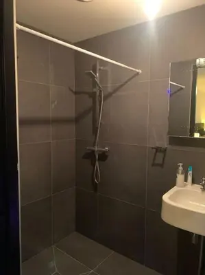 a shower with a glass door next to a sink at tuinhuis in Harmelen
