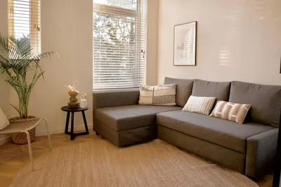 a gray couch in a living room with a window at Luxury room with private bathroom on great location. in Amsterdam