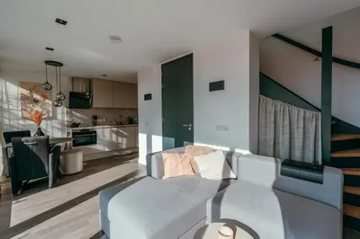 a living room with a couch and a kitchen at Bos, duin en strand huisje in Noordwijk