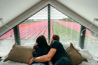 a man and woman sitting on a couch looking out a window at Bos, duin en strand huisje in Noordwijk