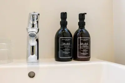 three bottles of alcohol sitting on a shelf in a bathroom at Hotel Bloemendaal by BHC in Bloemendaal