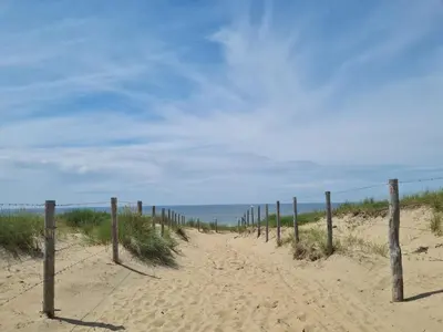 a fence on a sandy beach near the ocean at Hotel Bloemendaal by BHC in Bloemendaal