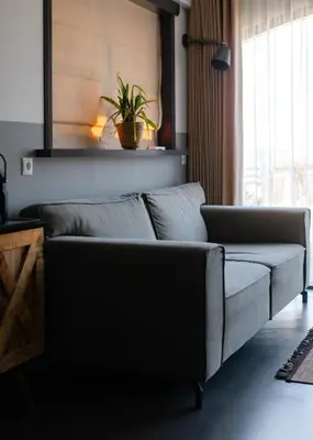 a couch in a living room with a plant at B&B Hartenlust kamer de Bedstee in Bodegraven