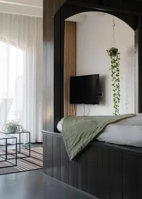 a bedroom with a bed with a tv on the wall at B&B Hartenlust kamer de Bedstee in Bodegraven