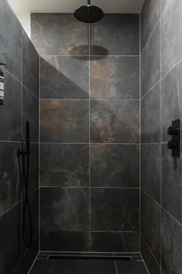 a bathroom with a shower with black tiles at B&B Hartenlust kamer de Bedstee in Bodegraven