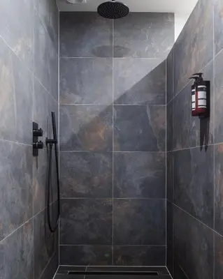 a bathroom with a shower with a light on the wall at B&B Hartenlust kamer de Boomgaard in Bodegraven