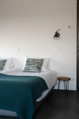 a bedroom with a bed with a green blanket and a stool at B&B Hartenlust kamer de Boomgaard in Bodegraven