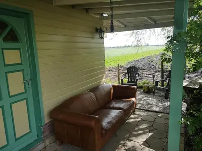 a leather couch sitting on the side of a house at Sweet Tiny House in Westbeemster