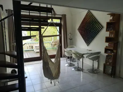 a hammock in a room with a table and a patio at Sweet Tiny House in Westbeemster