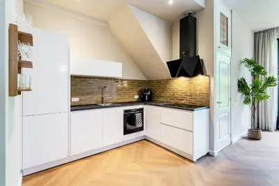 a kitchen with white cabinets and a brick wall at Stylish apartment next to the Amstel River - Unit A in Amsterdam