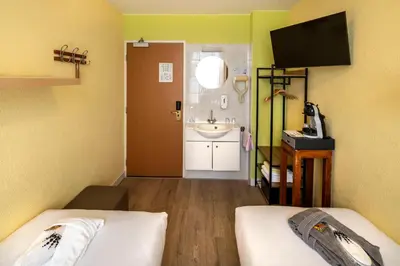 a room with two beds and a bathroom with a sink at Jupiter Hotel in Amsterdam