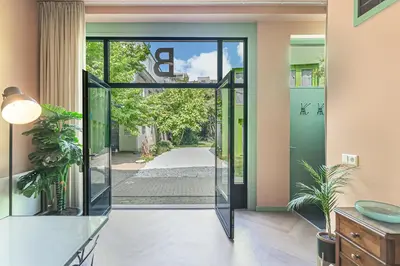 a glass pivot door in a house with a hallway at Stylish apartment next to the Amstel River - Unit B in Amsterdam
