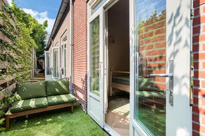 an open door to a patio with a bench on the grass at Stylish apartment next to the Amstel River - Unit B in Amsterdam