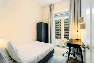 a bedroom with a bed and a desk and a window at Stylish apartment next to the Amstel River - Unit C in Amsterdam