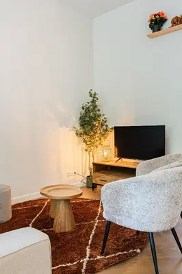 a living room with a chair and a table and a tv at Stylish apartment next to the Amstel River - Unit C in Amsterdam