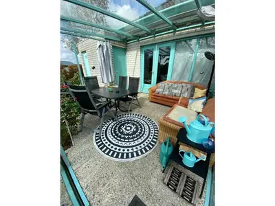 an inside view of a greenhouse with a table and chairs at Noordzee omheind met hond in Dirkshorn