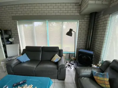 a living room with a leather couch and a stove at Noordzee omheind met hond in Dirkshorn