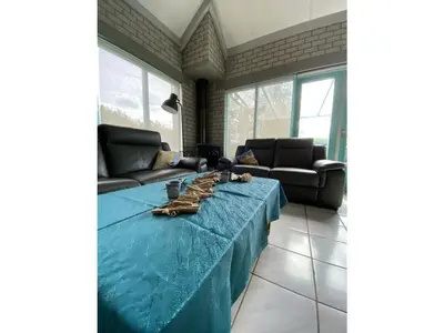 a living room with a blue table and a couch at Noordzee omheind met hond in Dirkshorn