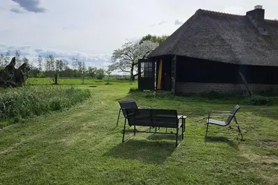 two chairs sitting in the grass next to a building at Natuurhuisje op Landgoed Groot Diermen in Putten