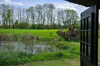 an open door to a field with a pond at Natuurhuisje op Landgoed Groot Diermen in Putten