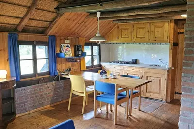 a kitchen with a wooden table and blue chairs at Natuurhuisje op Landgoed Groot Diermen in Putten