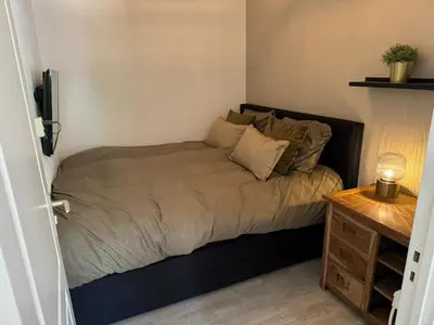 a bed in a small room with a night stand at Malu in Zandvoort