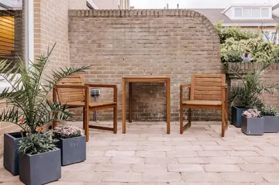 a patio with two chairs and a brick wall at Malu in Zandvoort