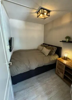 a small bedroom with a bed and a table at Malu in Zandvoort