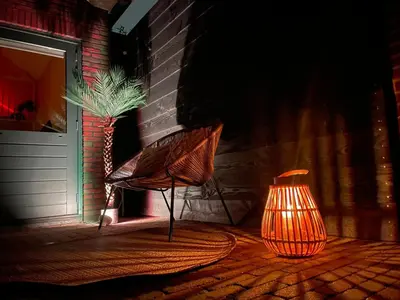 a lamp and a chair next to a building with a plant at Nieuwe vakantie woning nabij het strand - Egmond at the Beach House in Egmond aan Zee