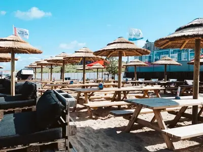 a group of picnic tables with umbrellas on a beach at Nieuwe vakantie woning nabij het strand - Egmond at the Beach House in Egmond aan Zee