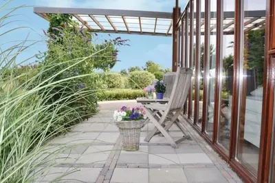 a patio with a chair and a table with flowers at Marina VILLA nabij water met prive sauna. in Spakenburg