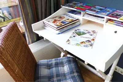 a table with a pile of books and a chair at Marina VILLA nabij water met prive sauna. in Spakenburg