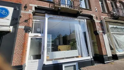 a window with white curtains on a brick building at BnB Souterrain in Amsterdam