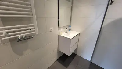a white bathroom with a sink and a mirror at BnB Souterrain in Amsterdam