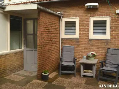 two chairs and a table in front of a brick building at On the coast Comfortable holiday residence in Egmond aan Zee