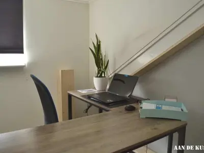 a laptop sitting on a wooden table in a room at On the coast Comfortable holiday residence in Egmond aan Zee
