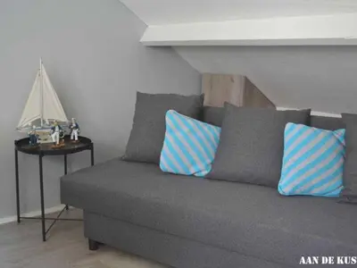 a couch with blue and white pillows in a room at On the coast Comfortable holiday residence in Egmond aan Zee